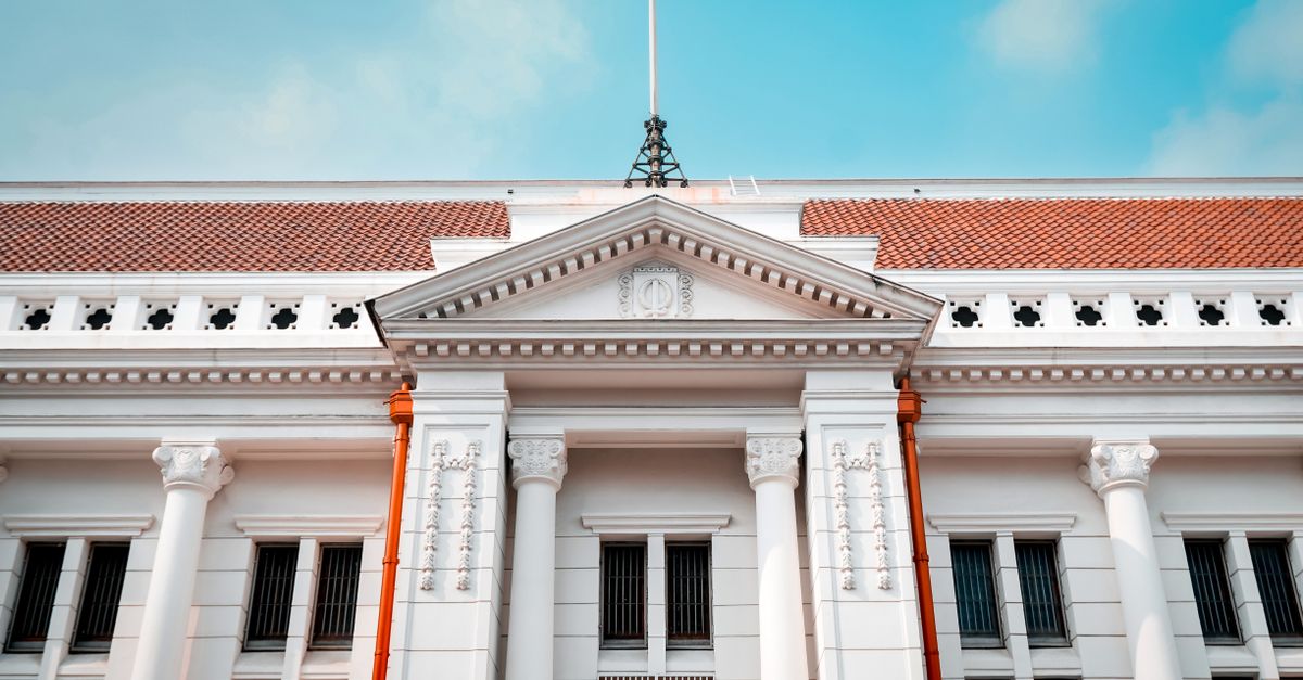 Elegant white facade of a historic building in Jakarta under a clear blue sky.