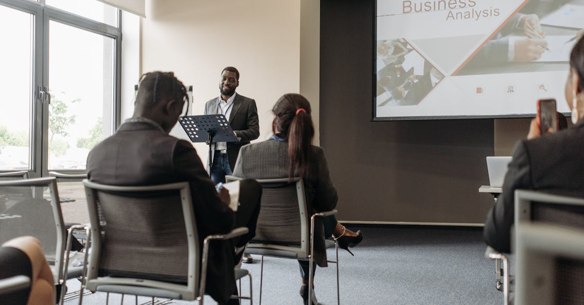 A business professional delivering a presentation in a conference room with diverse attendees.