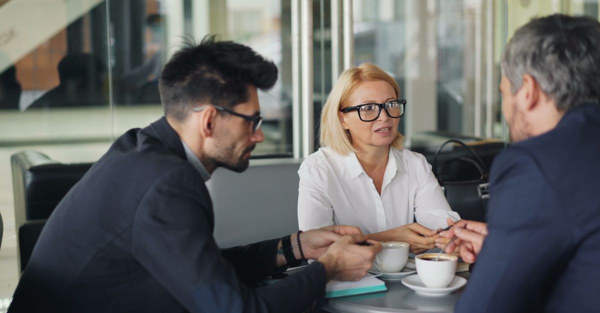 Professional team discussing ideas over coffee in a modern café setting.
