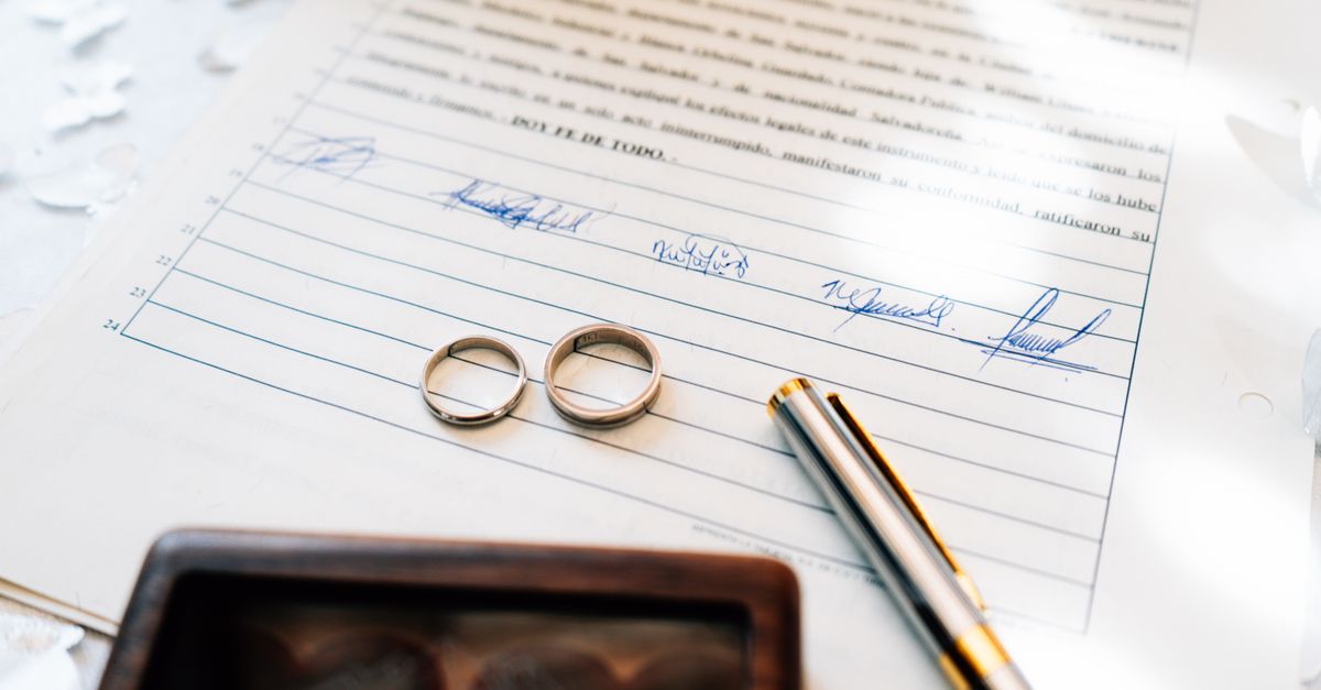Elegant wedding rings laid on a signed marriage certificate, symbolizing commitment.