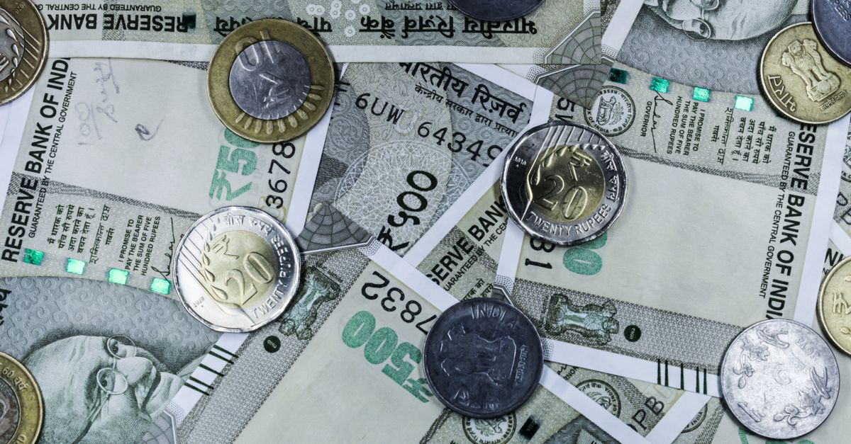Top view of various Indian rupee banknotes and coins, highlighting financial themes.