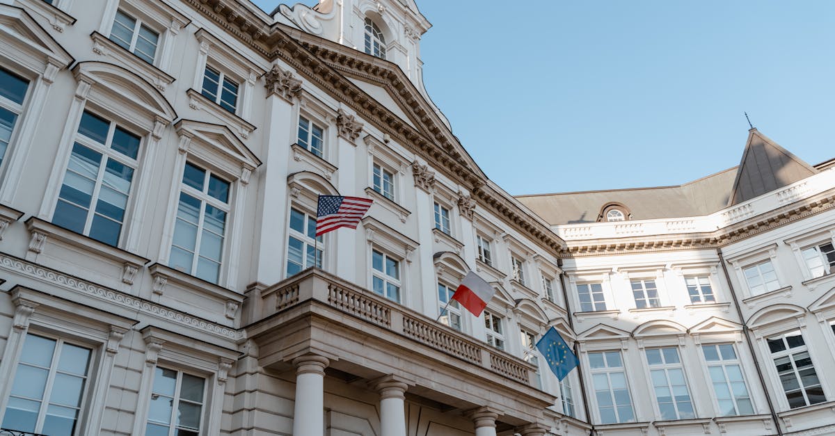 Low angle shot of a historic building with flags in an urban European district.