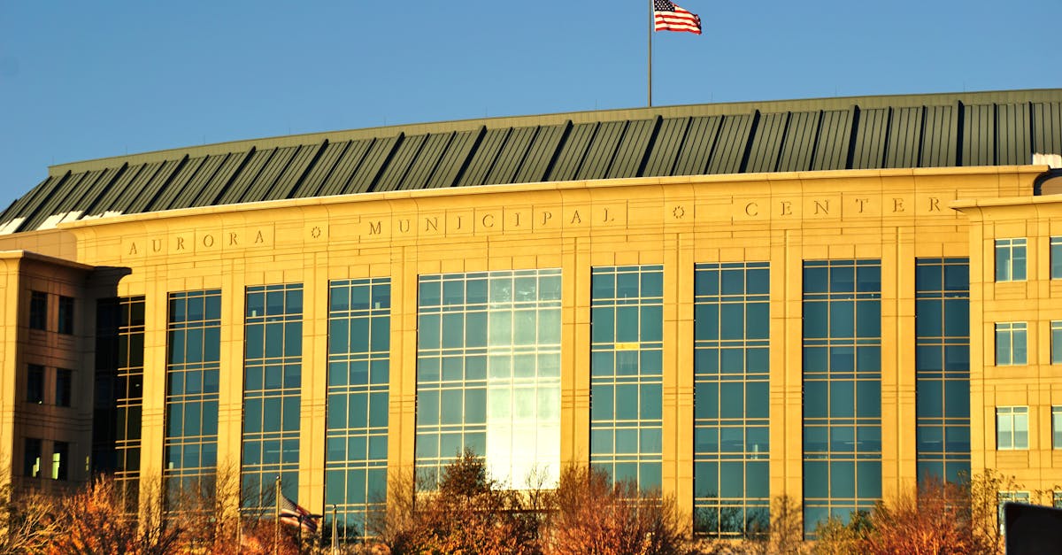 Aurora Municipal Center building with waving American flag in daylight.