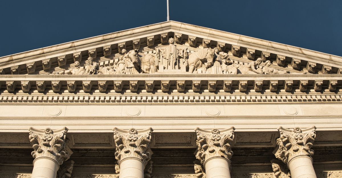 Close-up of neoclassical architecture in Madison, Wisconsin, showcasing ornate columns and pediment under a clear blue sky.