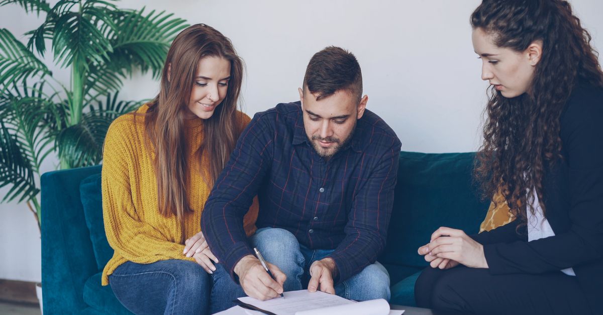 Young couple consults with financial advisor, signing important documents indoors.