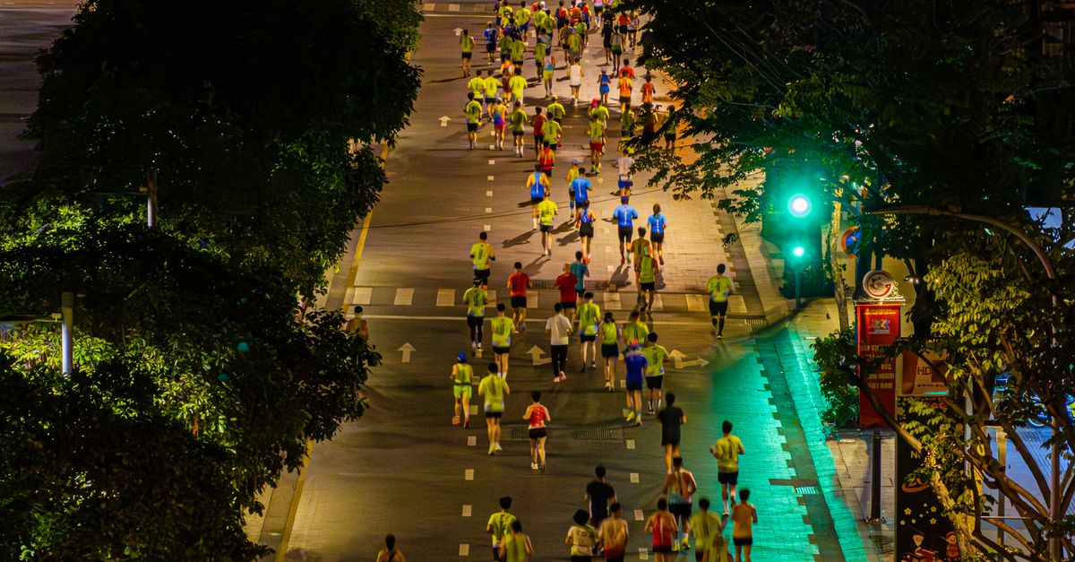Crowd of marathon runners at night from above, showcasing urban city life.