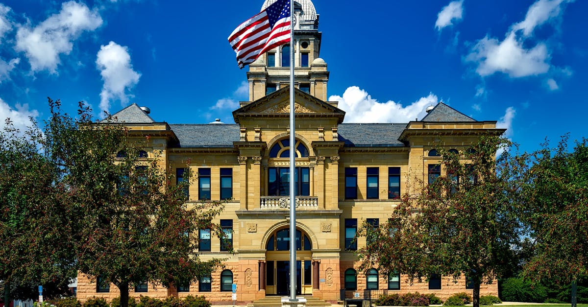 Grand courthouse in Cedar Rapids with an American flag in a bright blue sky.