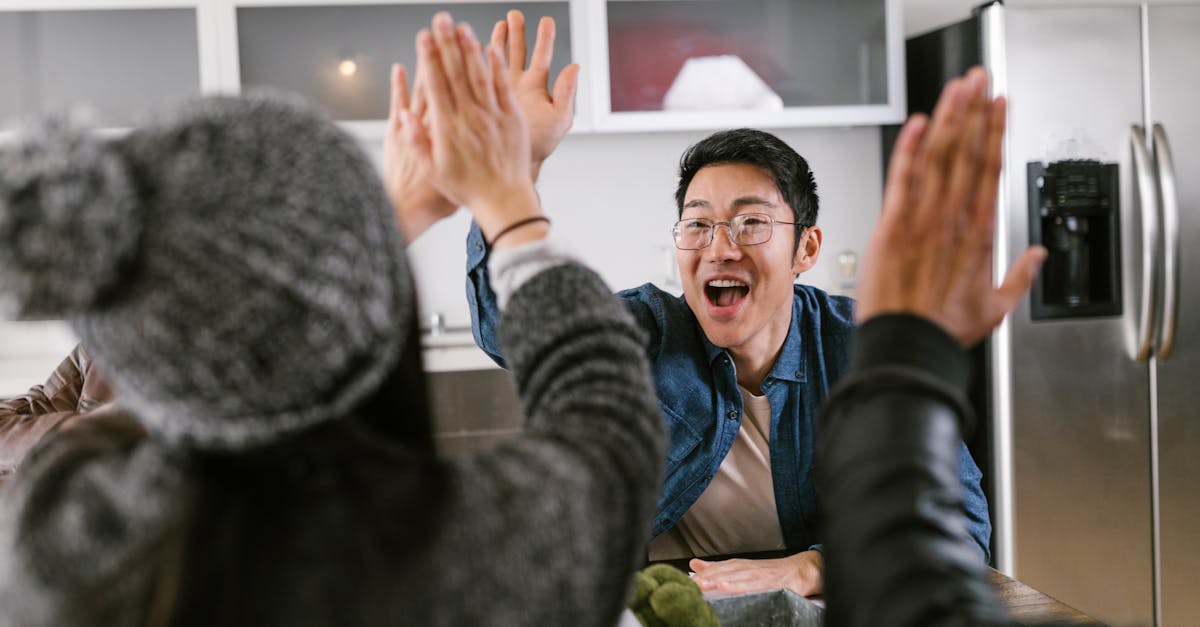 A diverse group of adults sharing a celebratory high five in a modern kitchen setting.