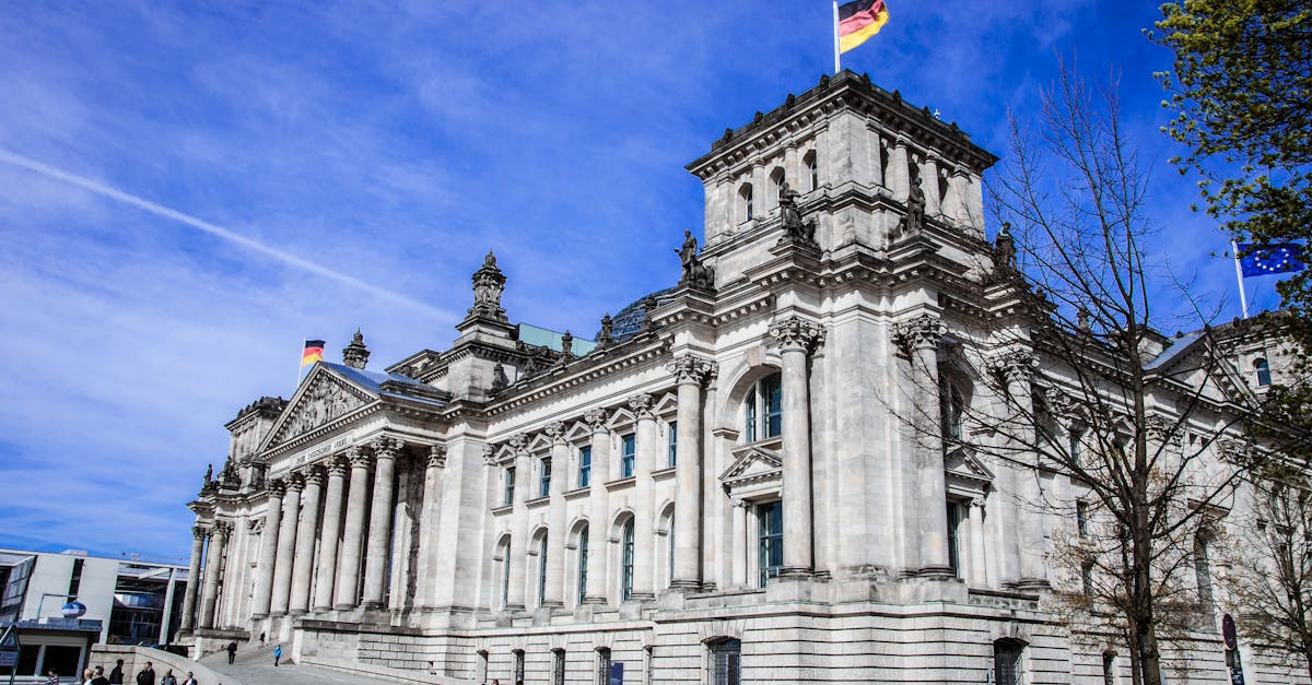 Reichstag building in Berlin with flags under a bright blue sky, showcasing government architecture.