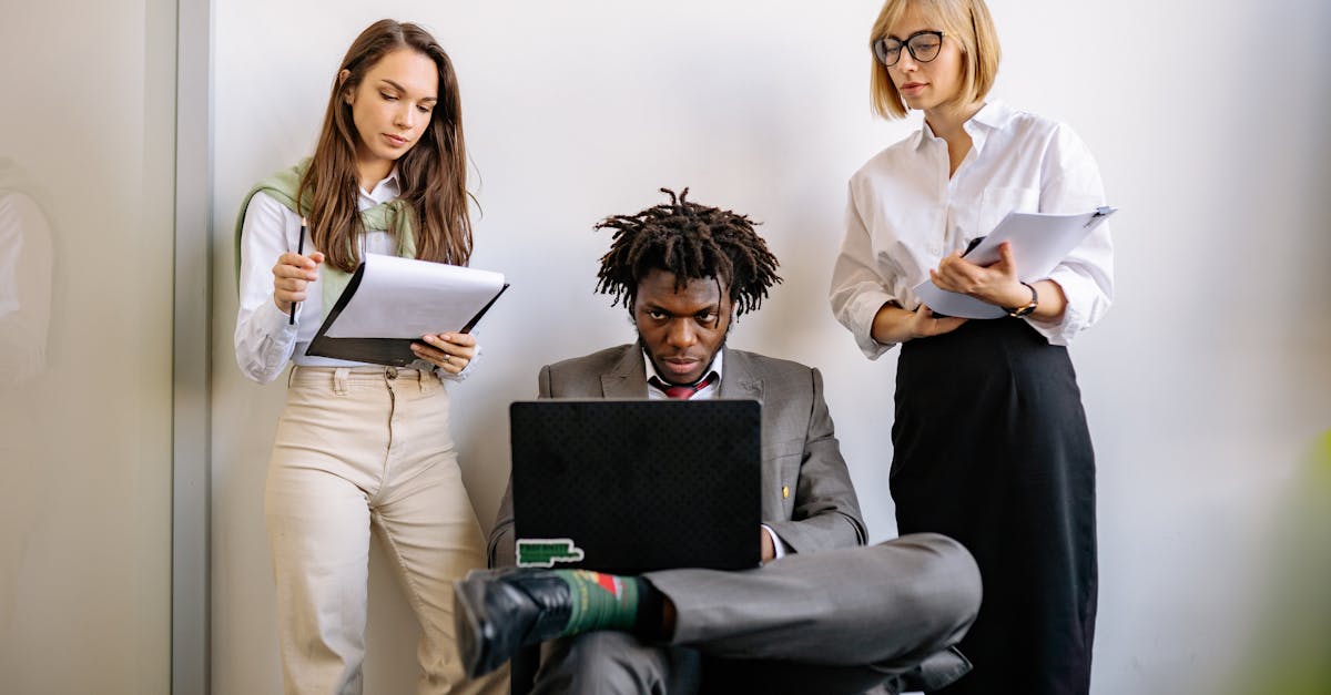 Three colleagues discussing project details around a laptop in a modern office setting.