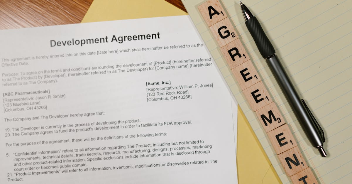Close-up of a development agreement document with pen and Scrabble tiles spelling 'AGREEMENT.'