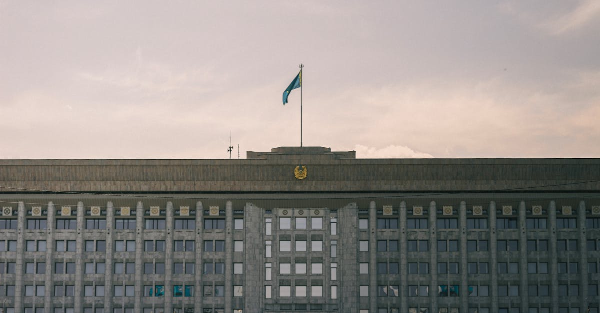 A grand government building with Kazakhstan flag in a clear sky.