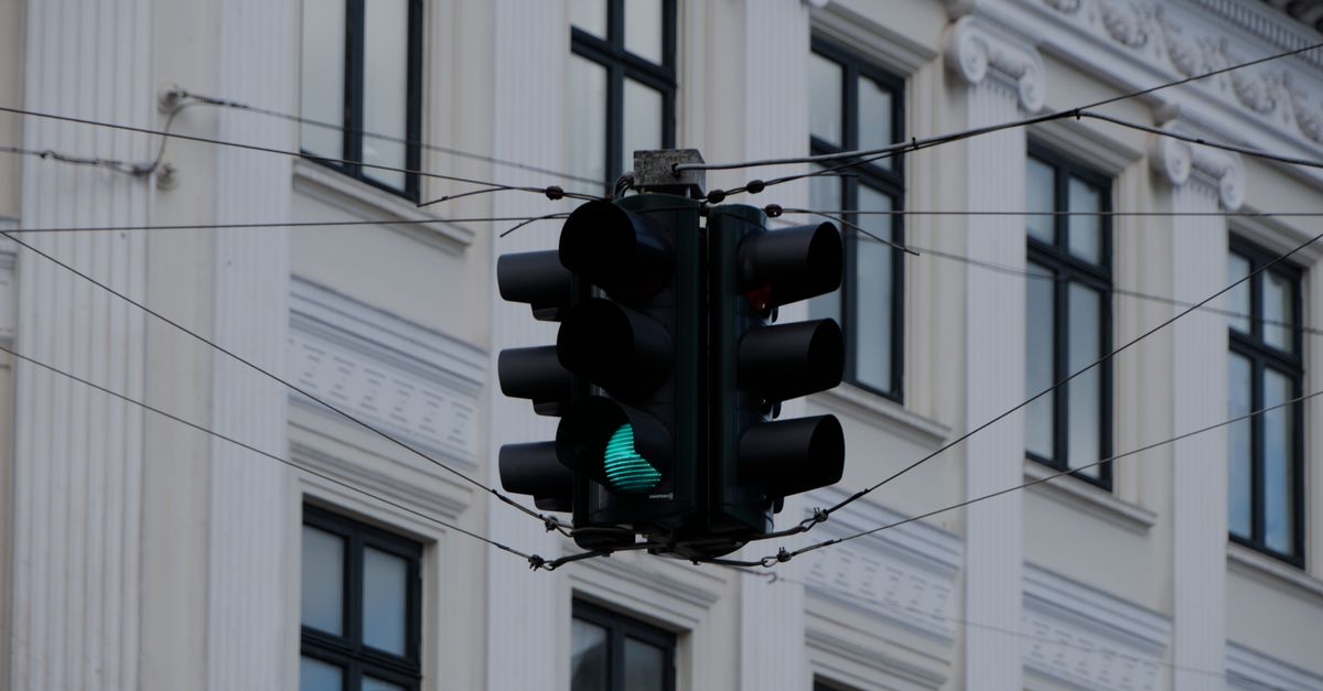Close-up of a traffic light with a green signal in front of a historic building facade.