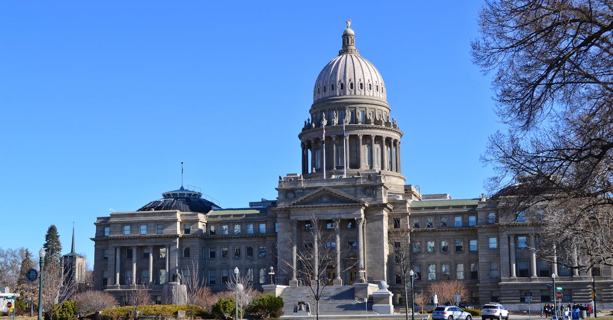 The Idaho State Capitol Building stands majestically under a clear blue sky with surrounding gardens.