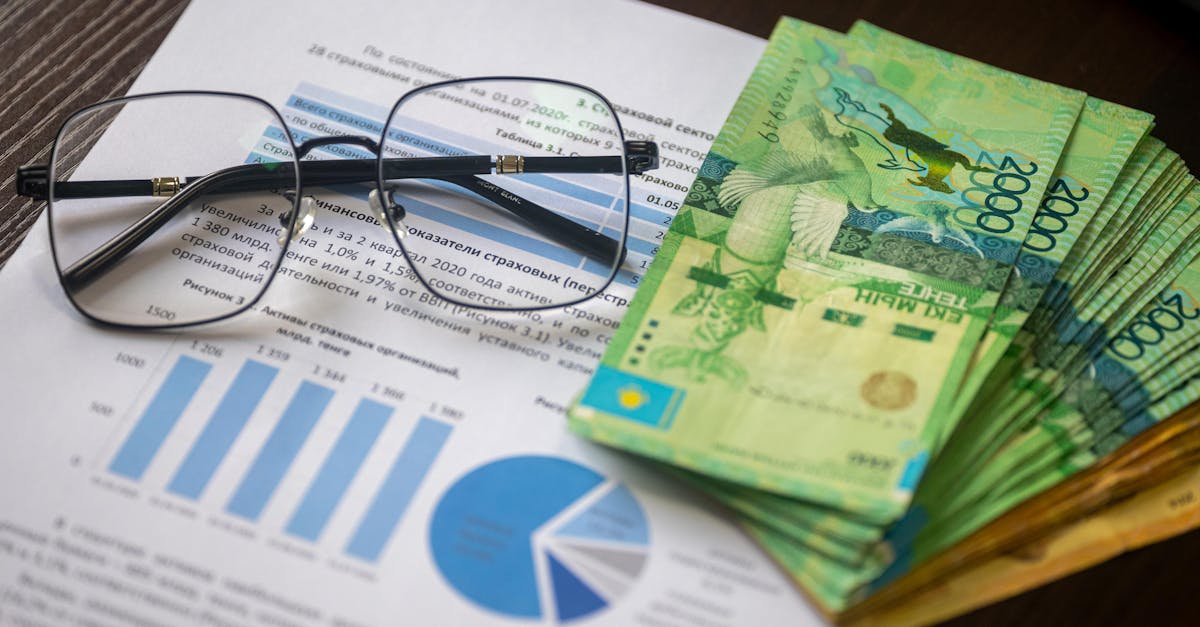 Kazakhstani tenge notes and financial reports on a desk, depicting financial analysis.
