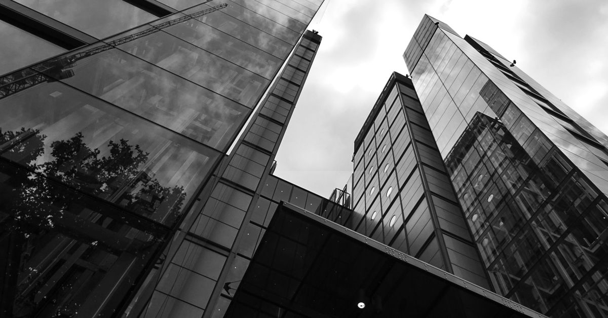 A low-angle view of sleek modern skyscrapers with glass facades against a cloudy sky.