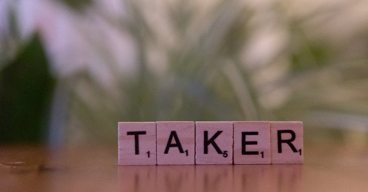 Close-up of Scrabble tiles spelling 'taker' on a blurred background, focus on letters.