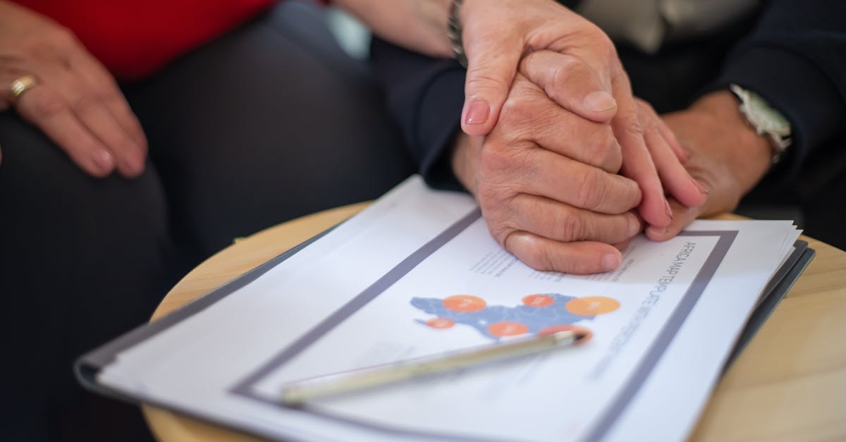 Two adults holding hands over business documents, symbolizing support and partnership.