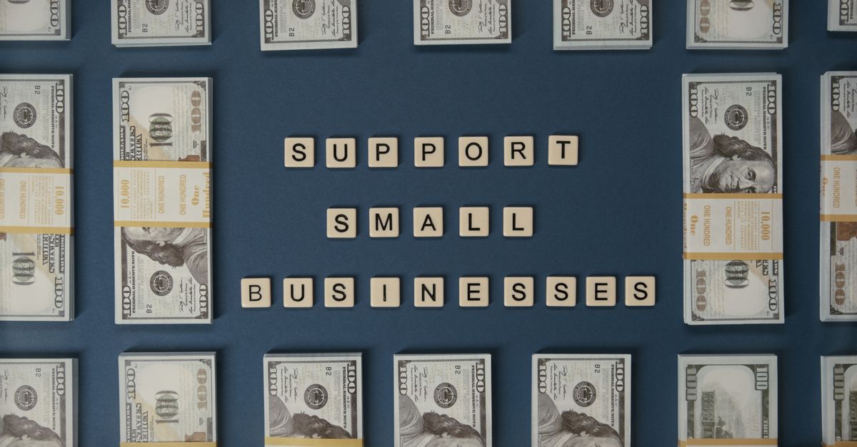 Top view of dollar bills and letter tiles promoting small businesses.