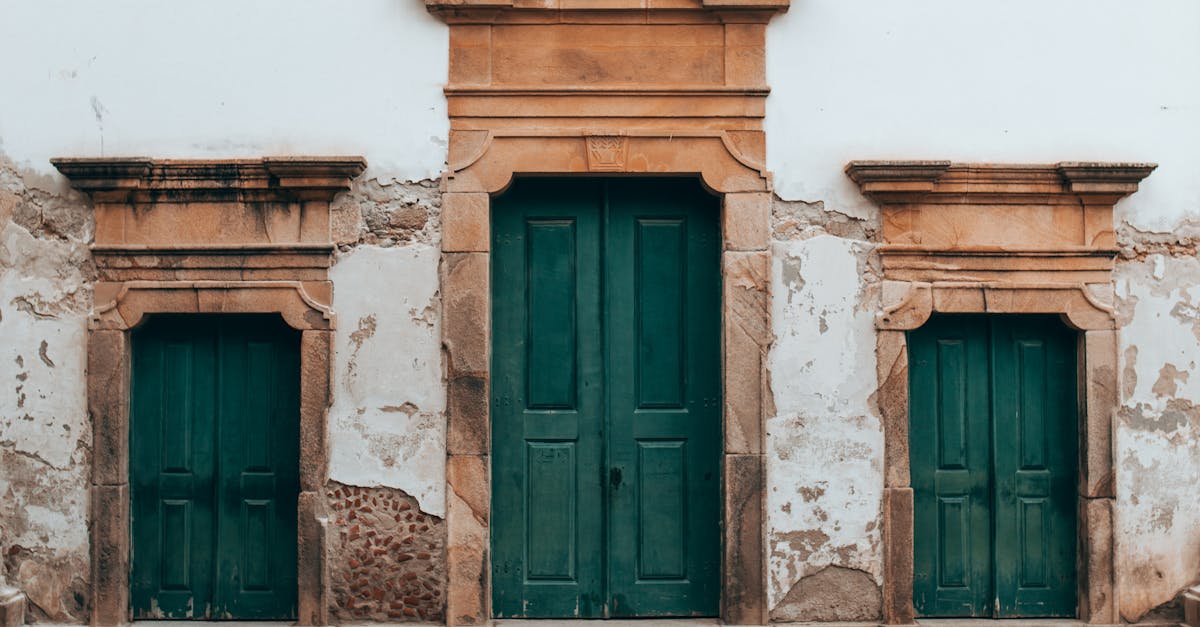 Symmetrical green doors set in a weathered, rustic stone wall showcasing historic architecture.