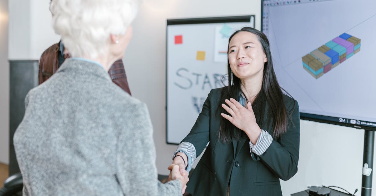 Professional women shaking hands in a corporate office setting, symbolizing a successful business agreement.