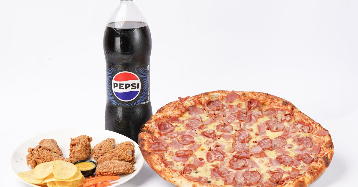 Tasty pepperoni pizza served with crispy chicken, chips, and Pepsi.