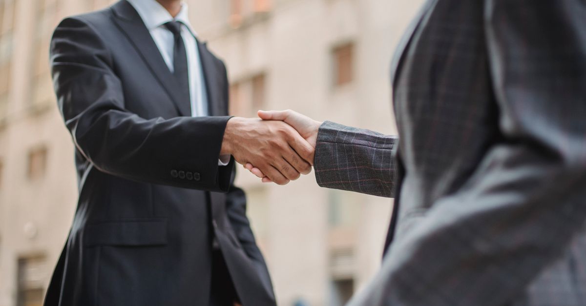Business professionals greeting each other with a handshake outdoors, symbolizing partnership.