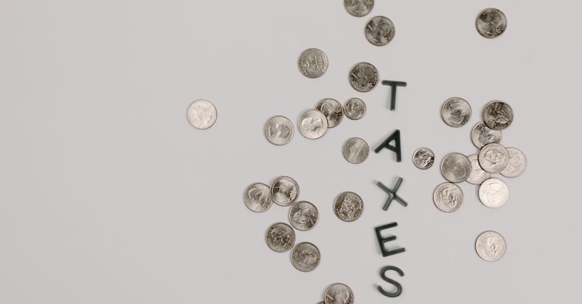 Scattered coins forming the word 'TAXES' on a white surface, symbolizing financial concepts.