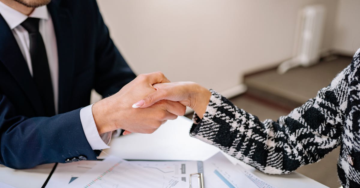 Close-up of a business handshake over documents in an office setting, symbolizing partnership.