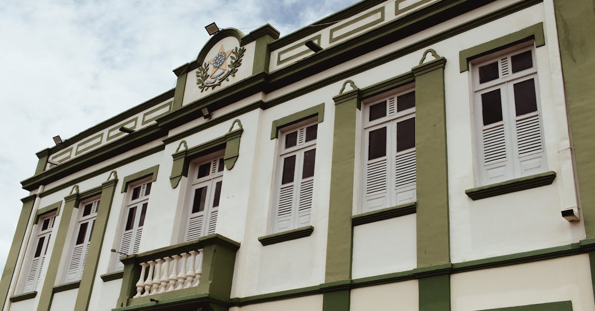 Low angle view of a classic building with ornate green facade and shuttered windows under a clear sky.