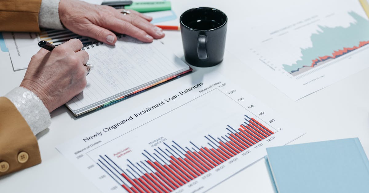 Close-up of a person analyzing financial charts and taking notes in an office setting.