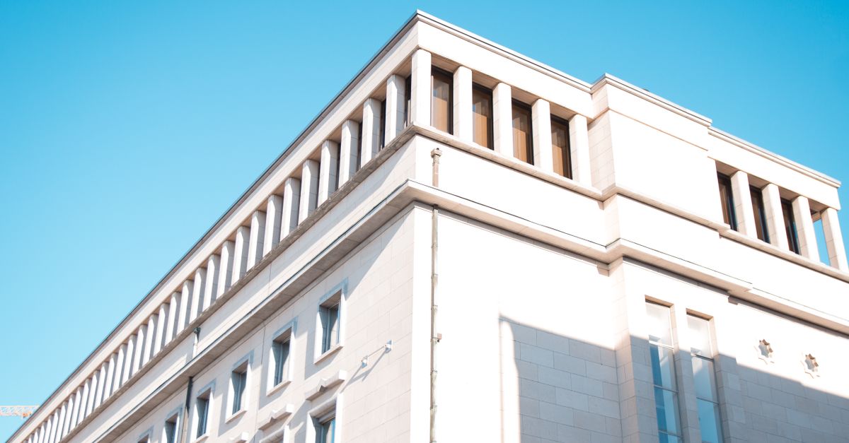 Low angle view of a modern building facade in Brussels with bright sunlight and blue sky.