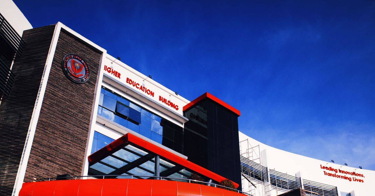 Low angle shot of a modern university building facade under a clear blue sky.