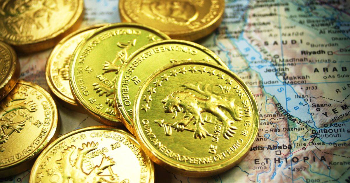 Stack of shiny gold coins placed on a world map, symbolizing global wealth.