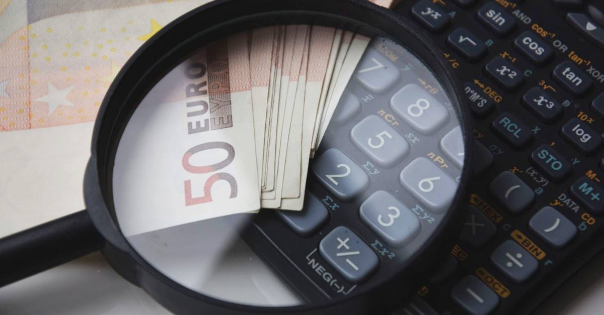 Euro bills under magnifying glass with calculator, symbolizing finance and analysis.