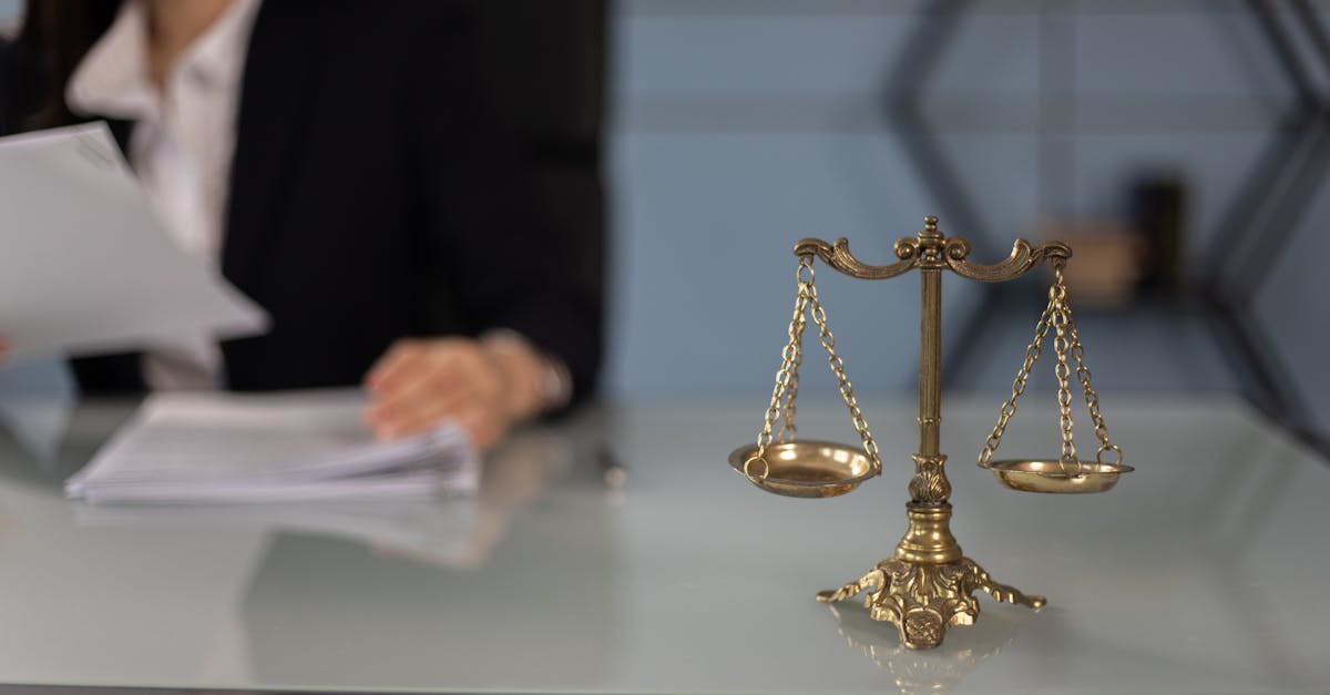 Balance scales on a desk in a professional office with a blurred businesswoman in the background.