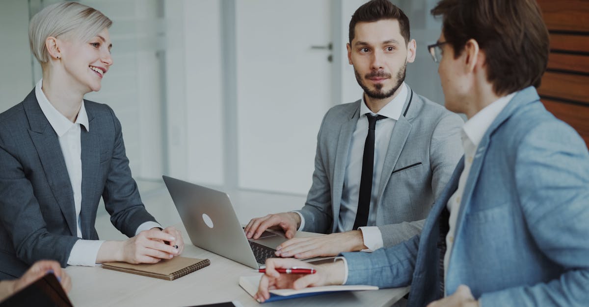 Business professionals in a meeting with laptops and notebooks, discussing strategy.