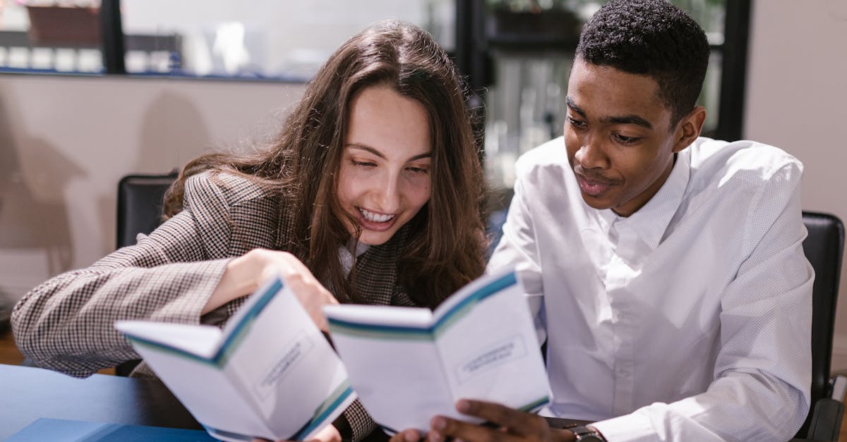 Two colleagues, a woman and a man, engaging in reading at an office setting.
