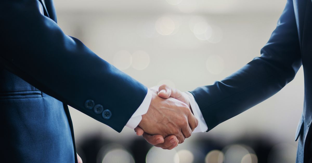 Close-up of business professionals in suits shaking hands, symbolizing a successful collaboration or agreement.
