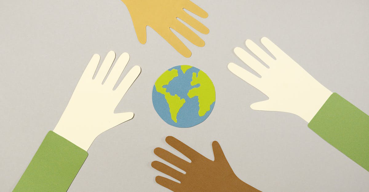 Colorful paper cutouts of diverse hands surrounding a small paper Earth, symbolizing unity.