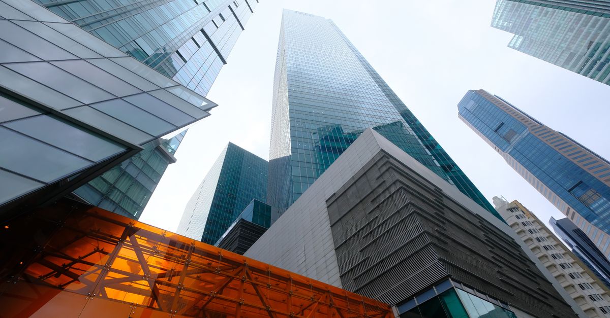 Low angle view of modern skyscrapers in an urban cityscape, showcasing glass facades and architectural design.