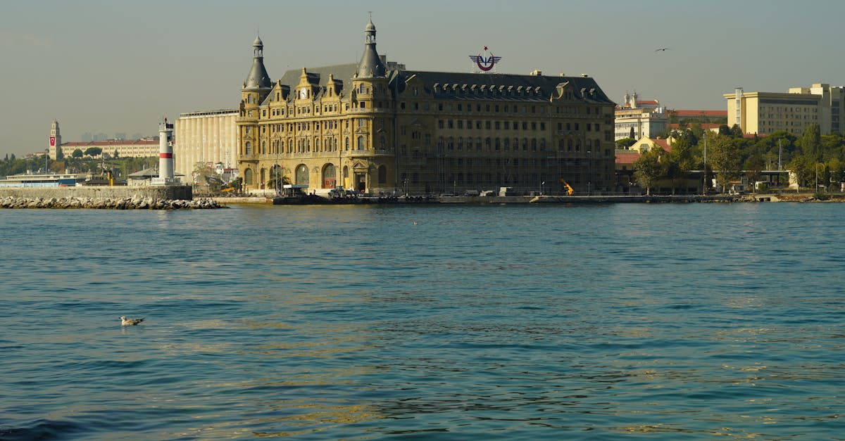 A scenic view of the historic Haydarpaşa Terminal in Istanbul with calm waters in the foreground.