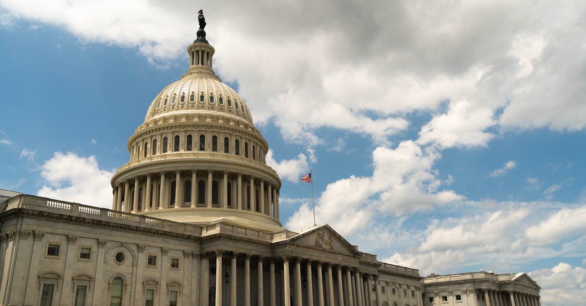 The United States Capitol building dome against a blue sky in Washington, DC, architectural landmark.