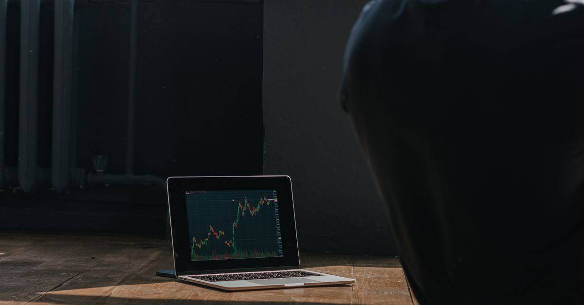 A person observing cryptocurrency trends on a laptop indoors.