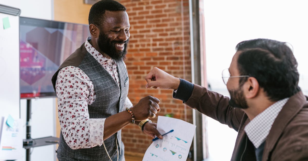 Two diverse businessmen share a fist bump at the office, symbolizing successful teamwork.