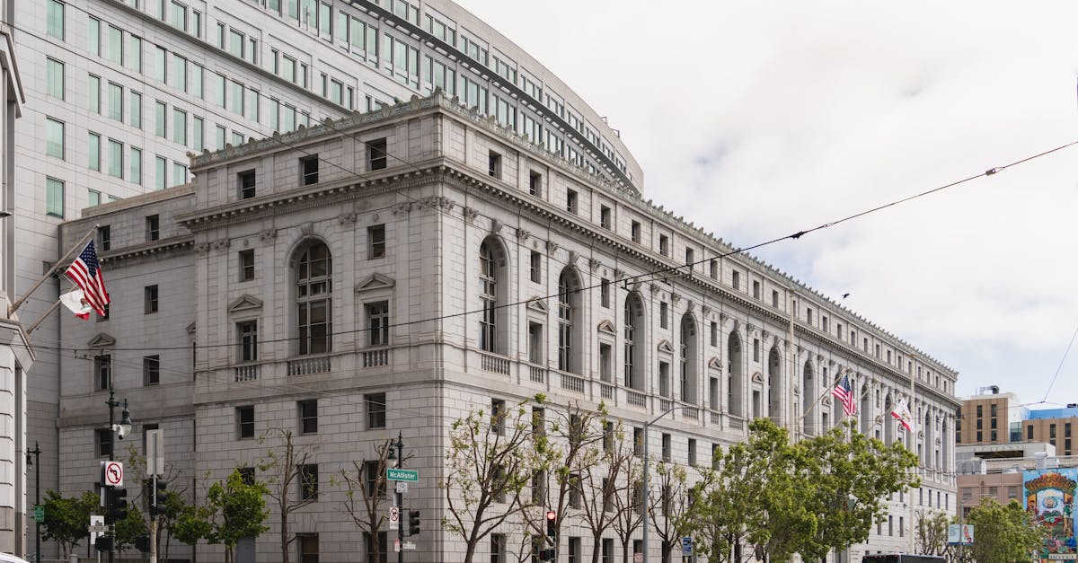 Elegant neoclassical courthouse in San Francisco with American flags outside.