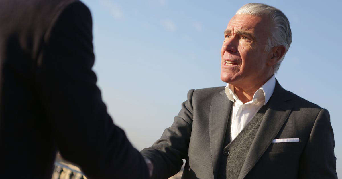 Elderly businessman shakes hands outdoors, symbolizing trust and cooperation.