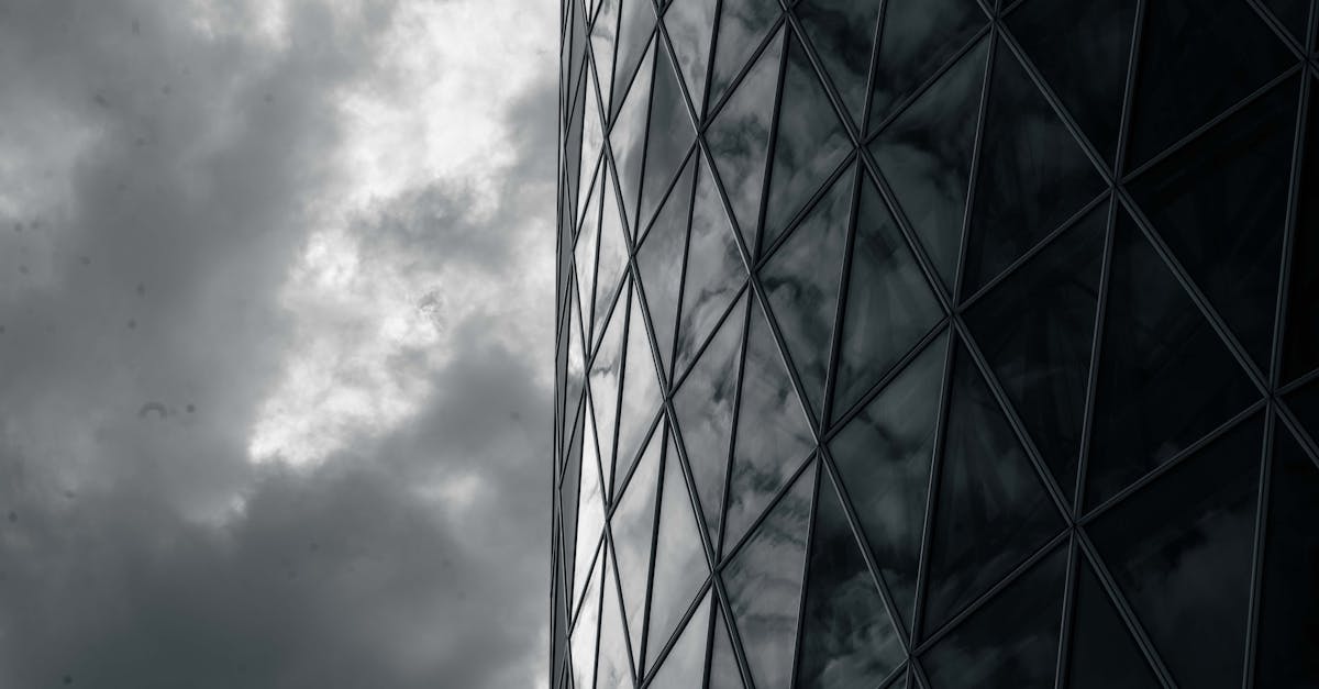 Dark glass facade reflects swirling clouds, creating a dramatic and abstract architectural view.