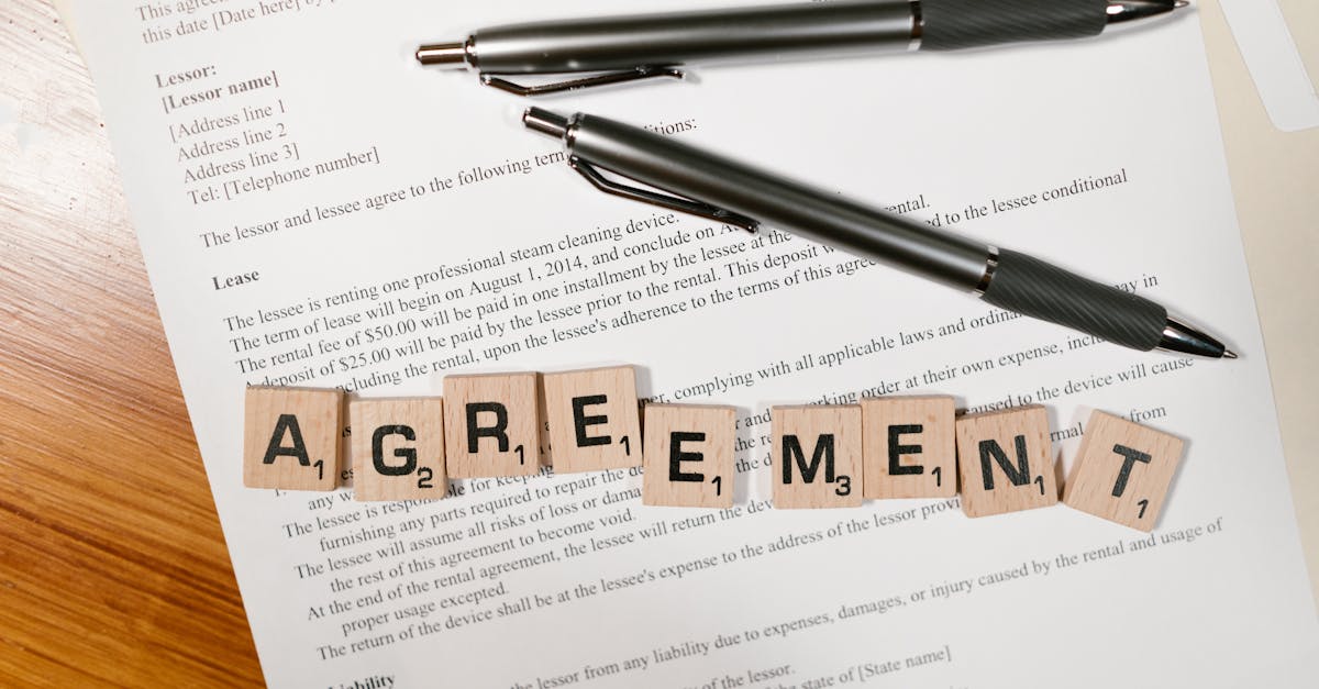 A document with Scrabble tiles spelling 'AGREEMENT' and two pens, symbolizing contract signing.