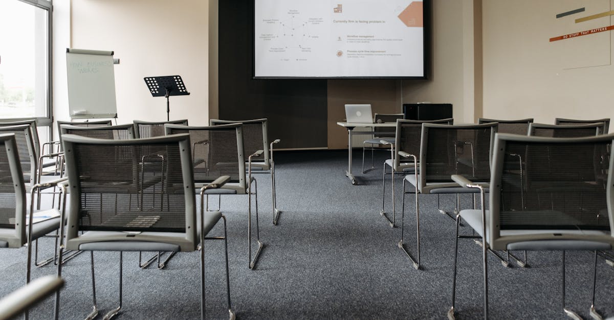 An empty conference room with chairs, a projector screen, and presentation setup.